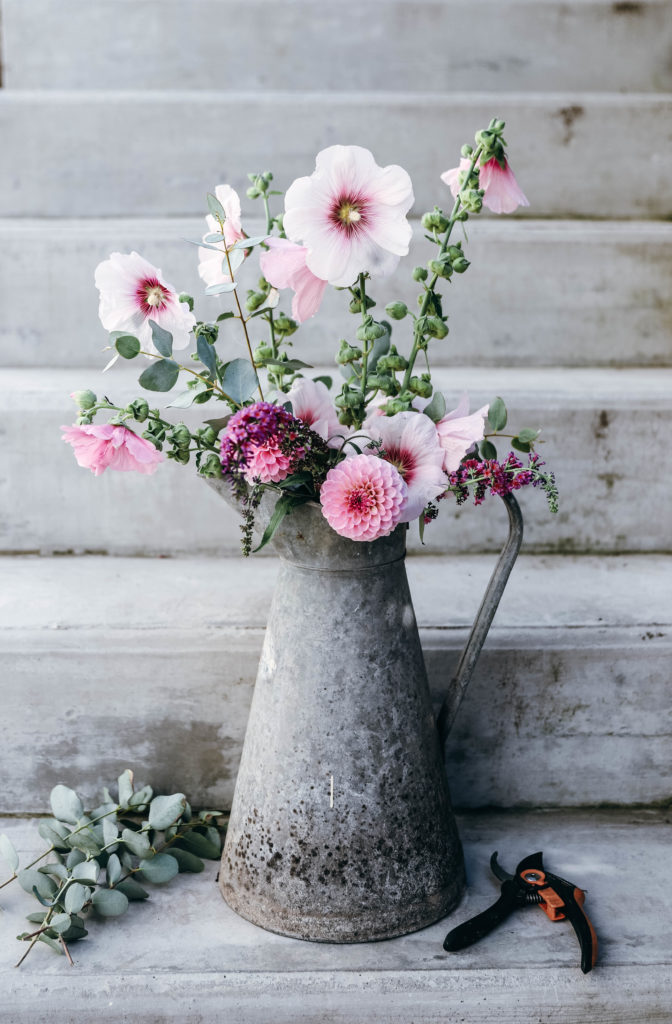 bouquet de grandes fleurs roses dans un pot à lait en zinc