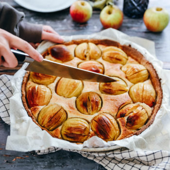 Photo avec une main qui découpe une tarte aux pommes