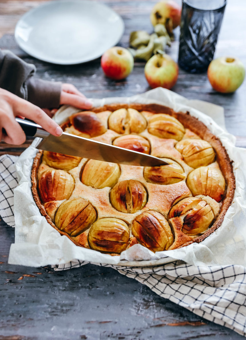 Photo avec une main qui découpe une tarte aux pommes