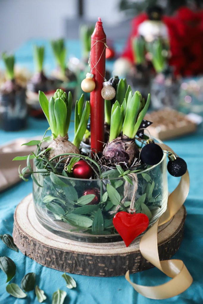décoration d'une table de Noël avec des fleurs, une bougie et des boules de Noël à paillettes