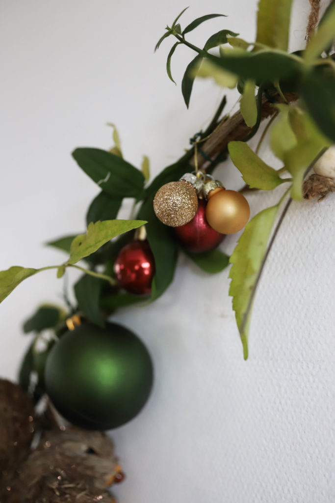 couronne de noël avec des branches, des feuilles et des boules de Noël à paillettes