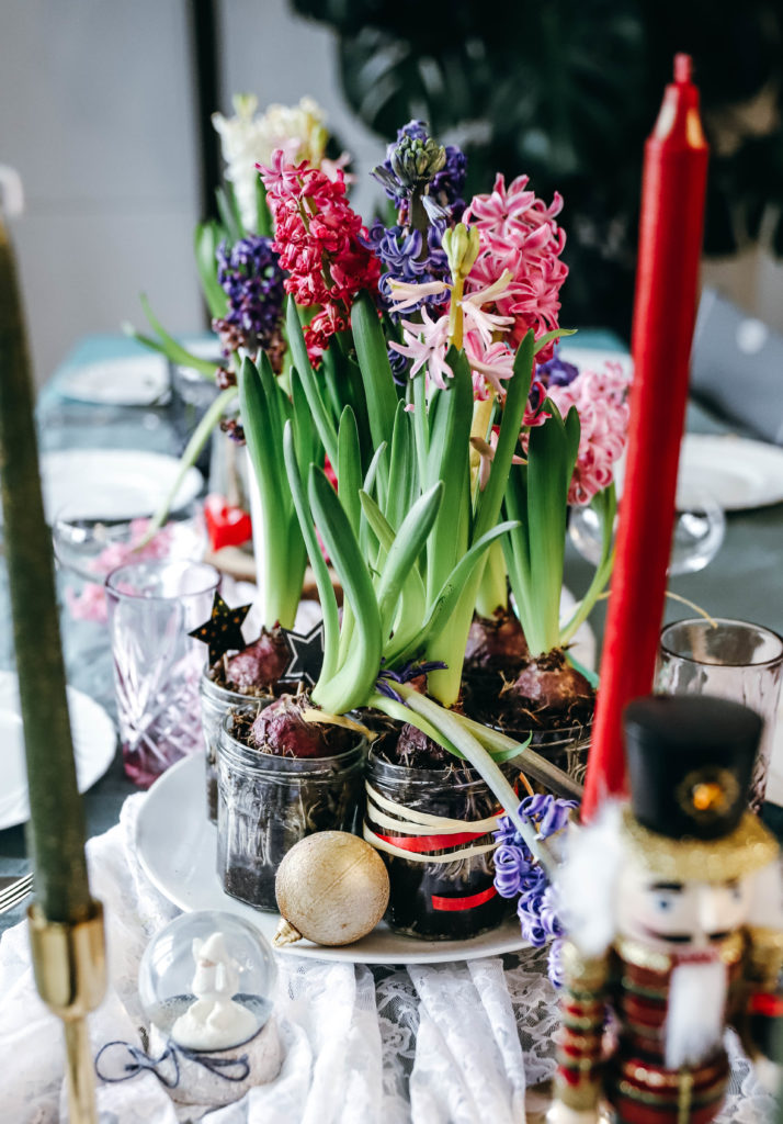 jacinthes roses, violettes et blanches plantées dans des pots en verre entourées de bougies
