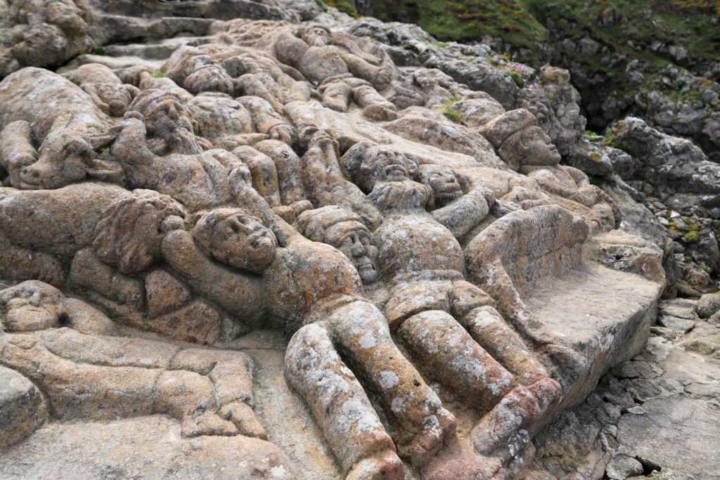 personnages sculptés dans les rochers de granite face à la mer