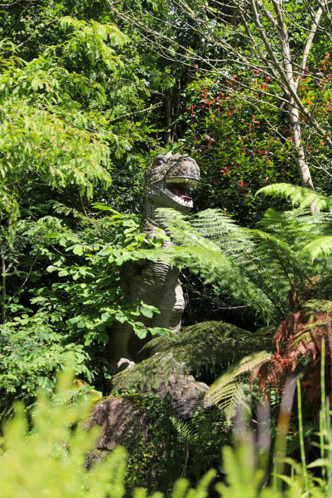 statue d'un dinosaure dans un jardin luxuriant