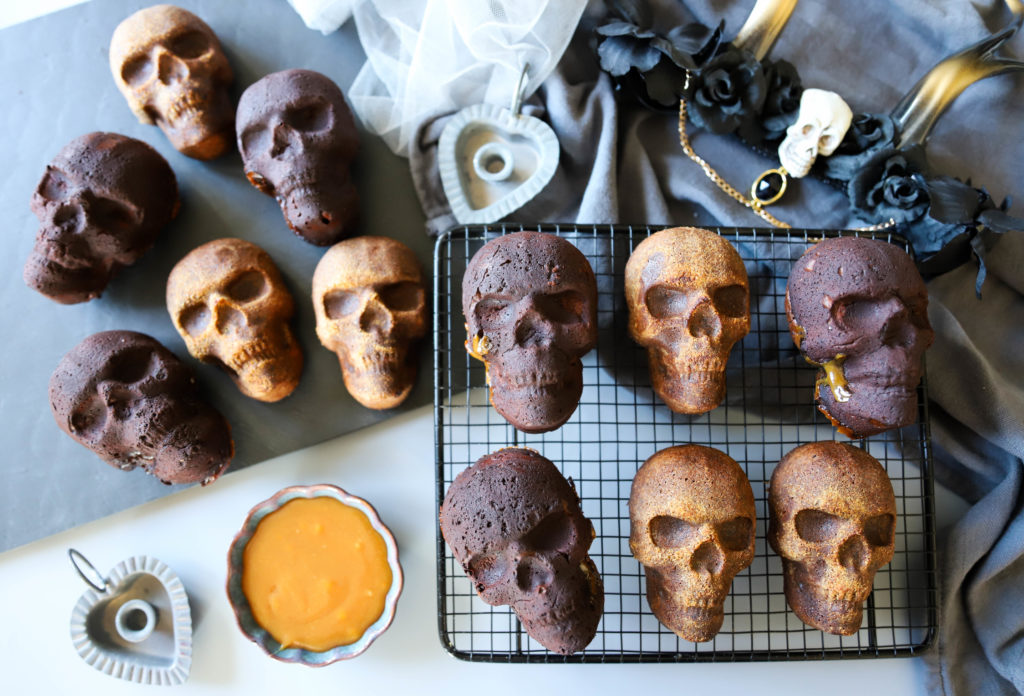 gâteaux en forme de tête de mort réalisés pour Halloween. Des cakes aux épices sont posés sur une table avec des tissus et voiles sombres