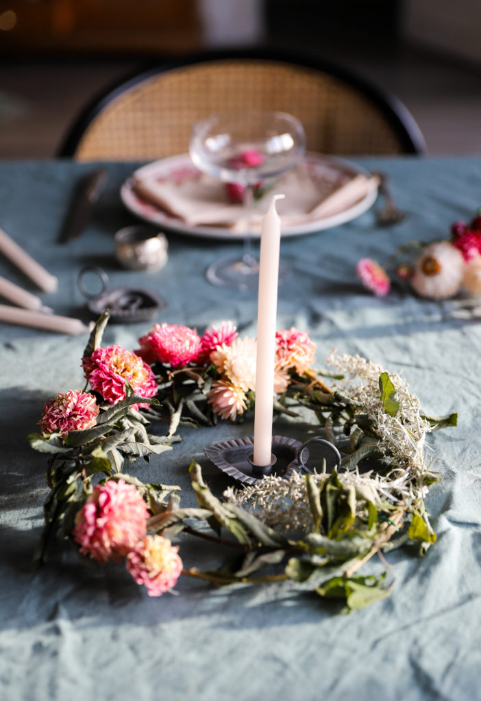 photo d'une table décorée de fleurs séchées. Le centre de table est une couronne avec une bougie au centre