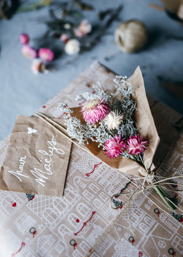 paquets cadeaux avec des petits bouquets de fleurs séchées accrochés dessus