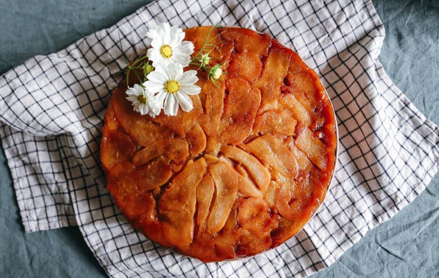 gateau aux poires caramélisées gâteau aux poires caramélisées doré avec une fleur comestible blanche sur le dessus pour décorer