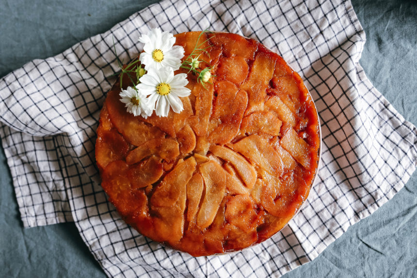gâteau aux poires caramélisées doré avec une fleur comestible blanche sur le dessus pour décorer